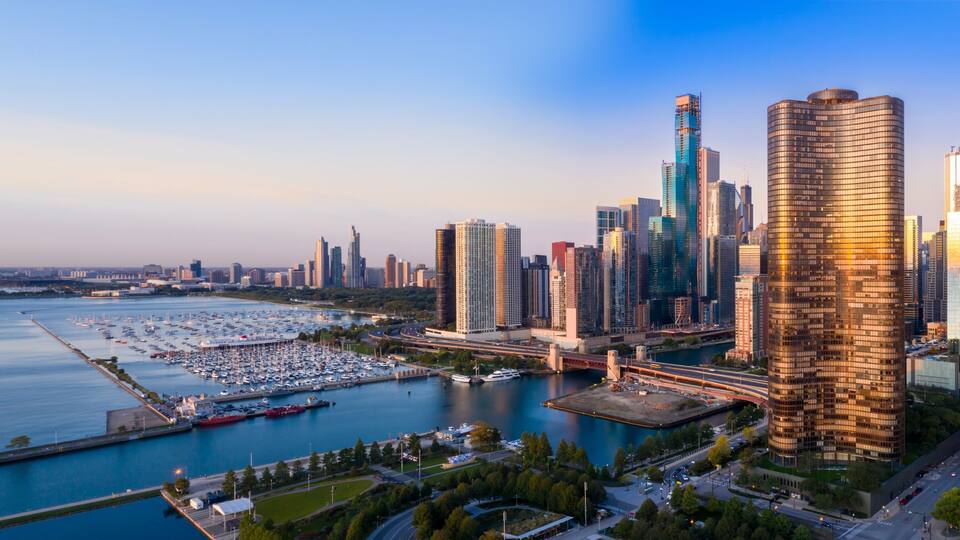 A city skyline with modern skyscrapers, a marina with boats, and a river.