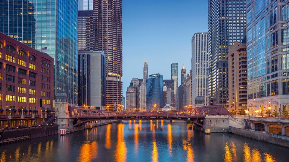 A cityscape with a river, modern buildings, and a bridge.