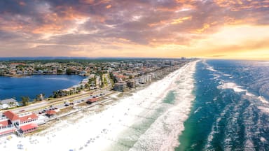 A coastal town with a beach, a marina, and a sunset over the ocean.