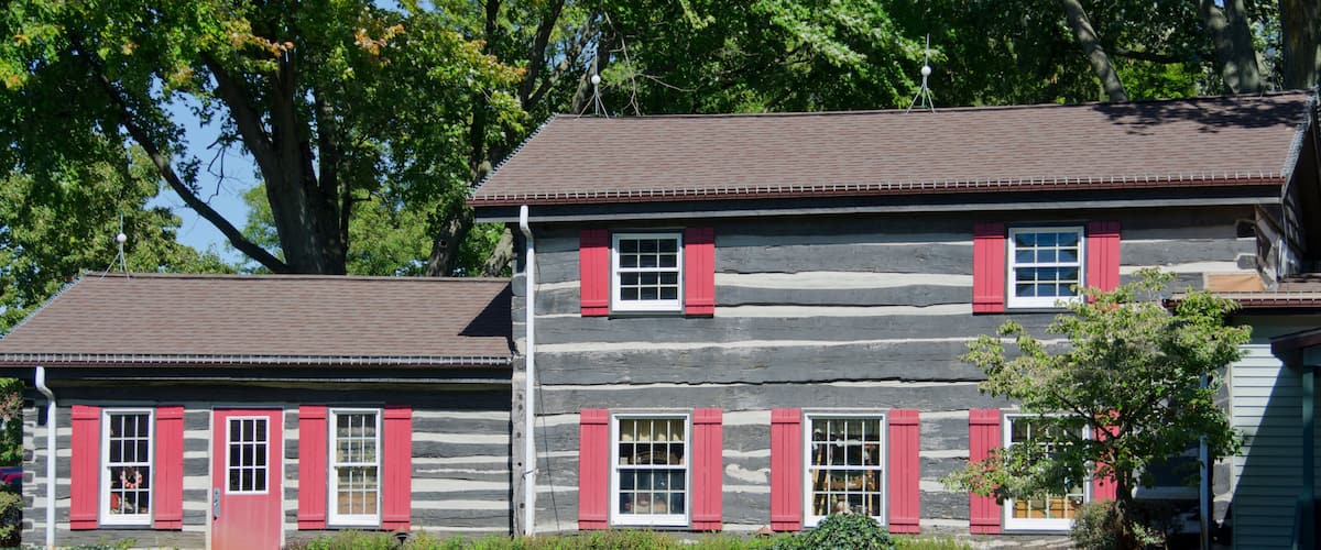 A log cabin with red shutters and a small porch.