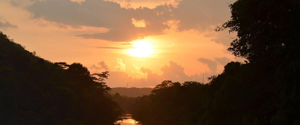 A sunset over a river flanked by dense foliage.