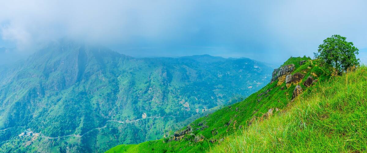 A mountainous landscape with lush greenery and a winding road.