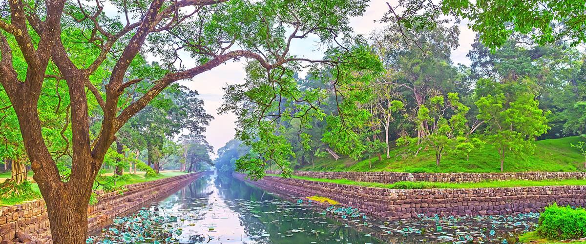 A canal flanked by stone walls and lush greenery.