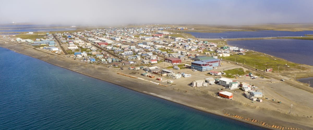 An aerial view of a coastal town with buildings, roads, and a harbor.