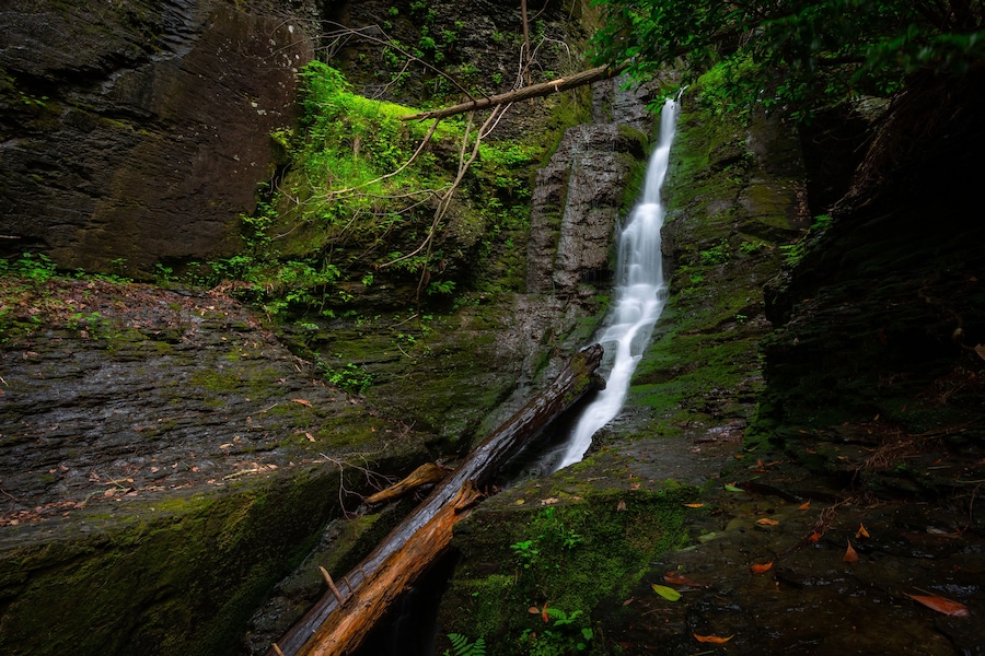 Silverthread narrow waterfall slow shutter speed in forest flowing down rocks with green moss horizontal