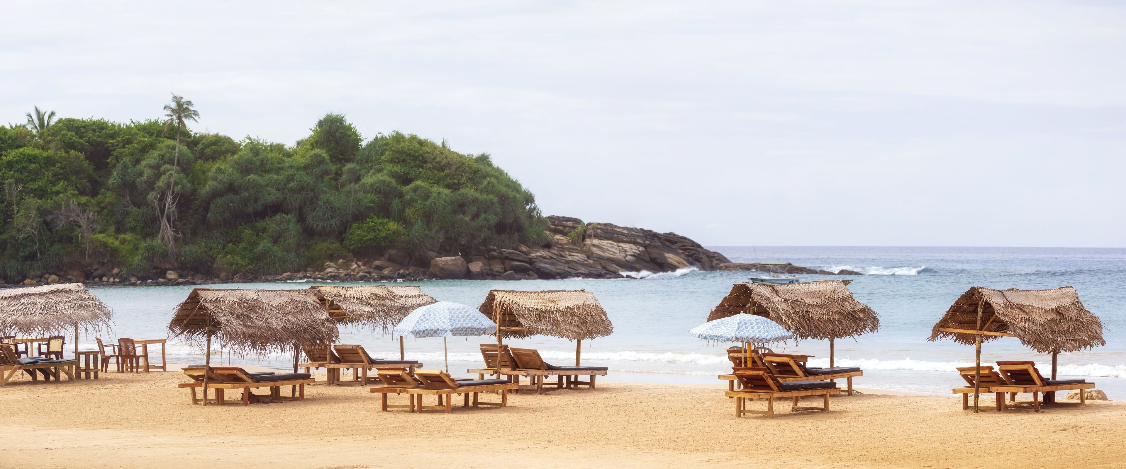 Tranquil Beach With Straw Umbrellas And Lounge Chairs In Sri Lanka