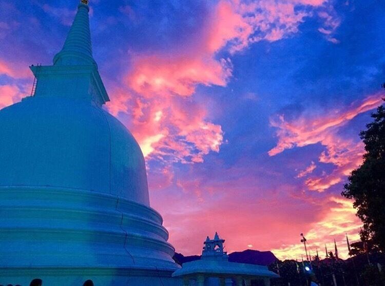 A large white dome structure against a colorful sunset sky.