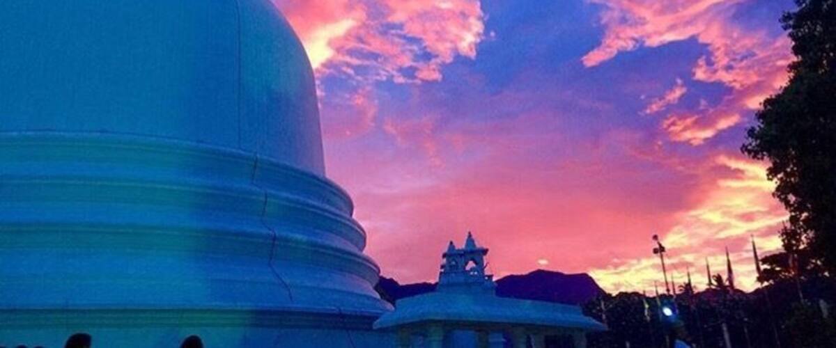 A large white dome structure against a colorful sunset sky.