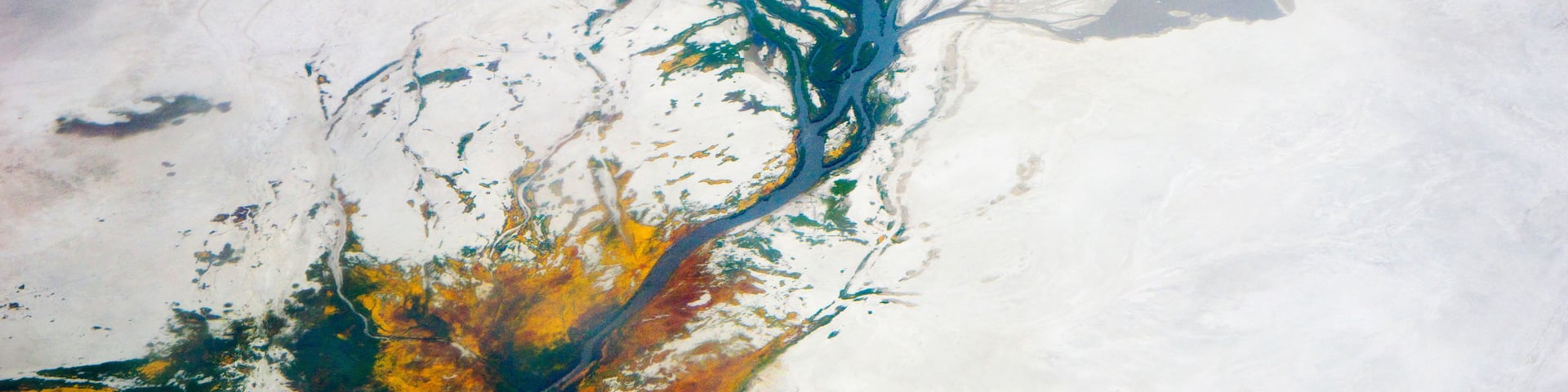 A colorful river delta empties into a lake with a white bank.