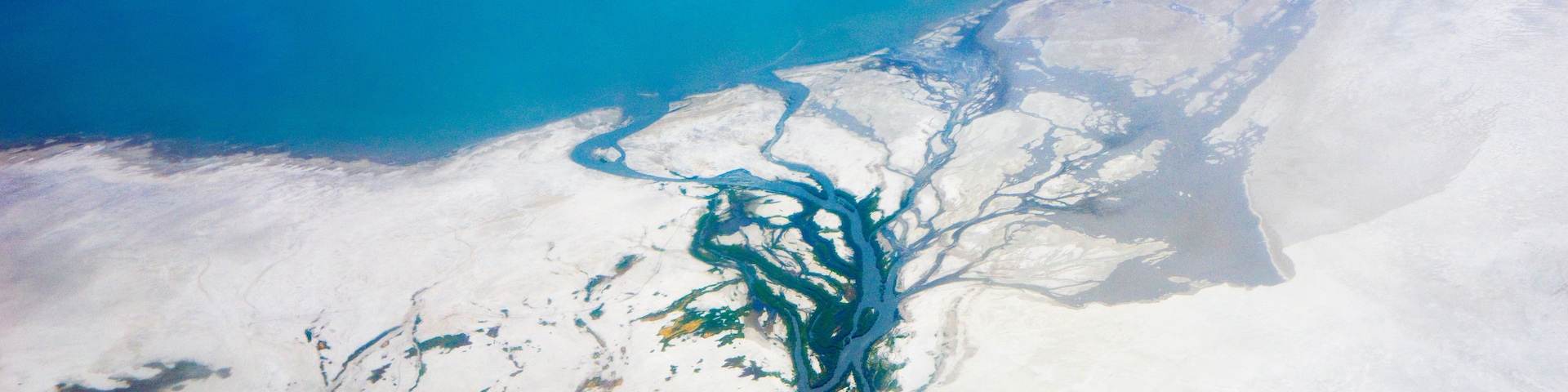 A river winding through a snowy landscape with a clear blue sky above.