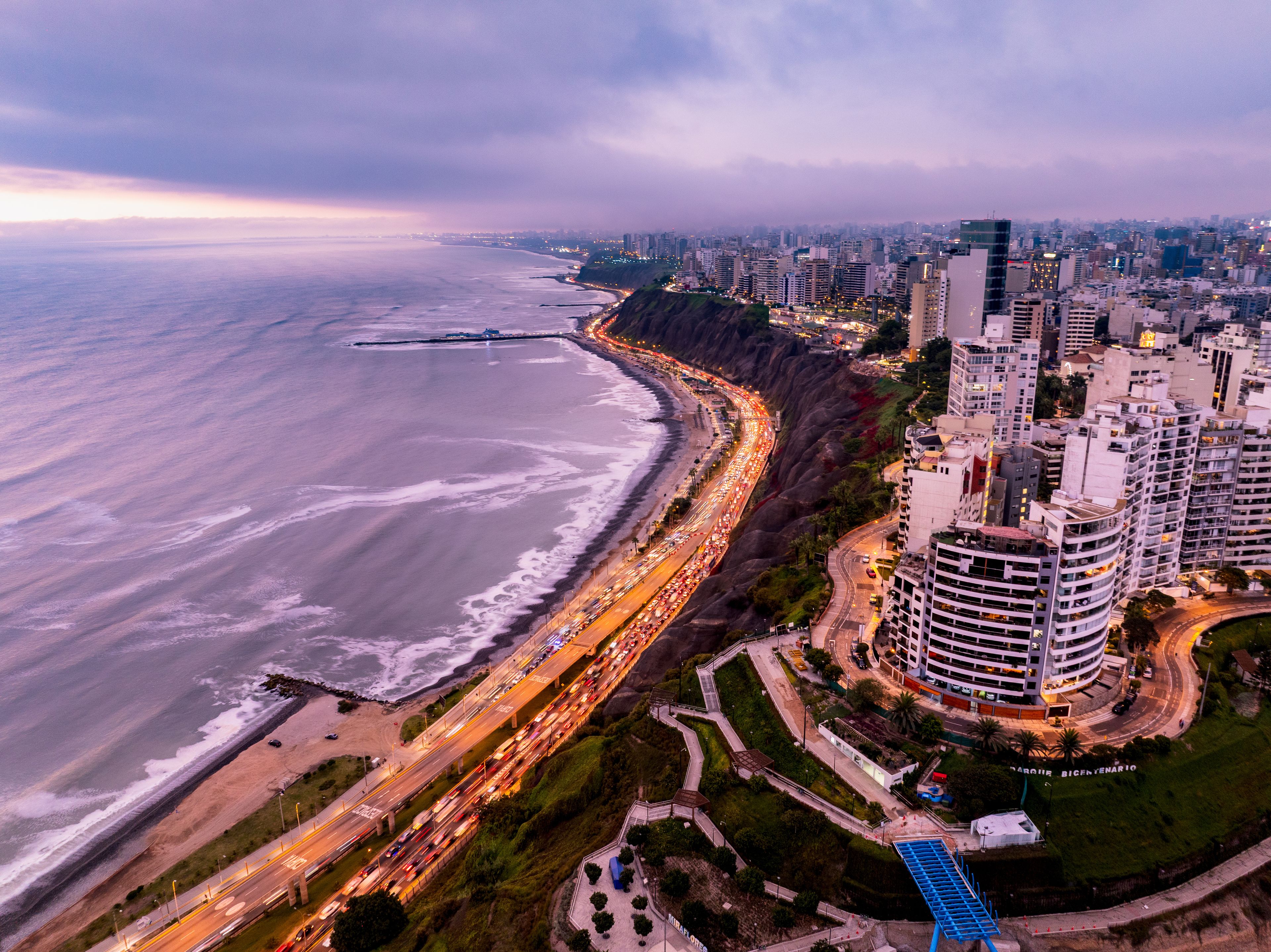 A coastal cityscape with a curved highway, a beach, and high-rise buildings.