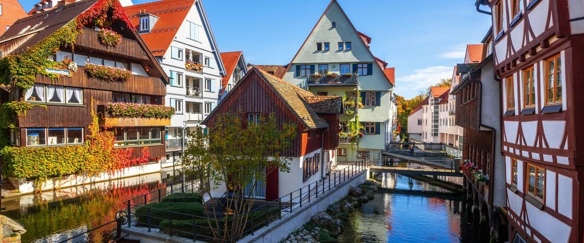 A narrow canal flanked by traditional half-timbered houses with steep roofs and flower boxes.