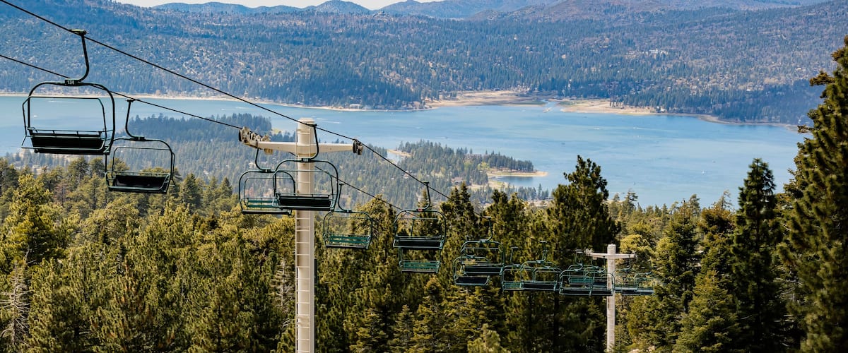 A cable car system with a lake and mountains in the background.