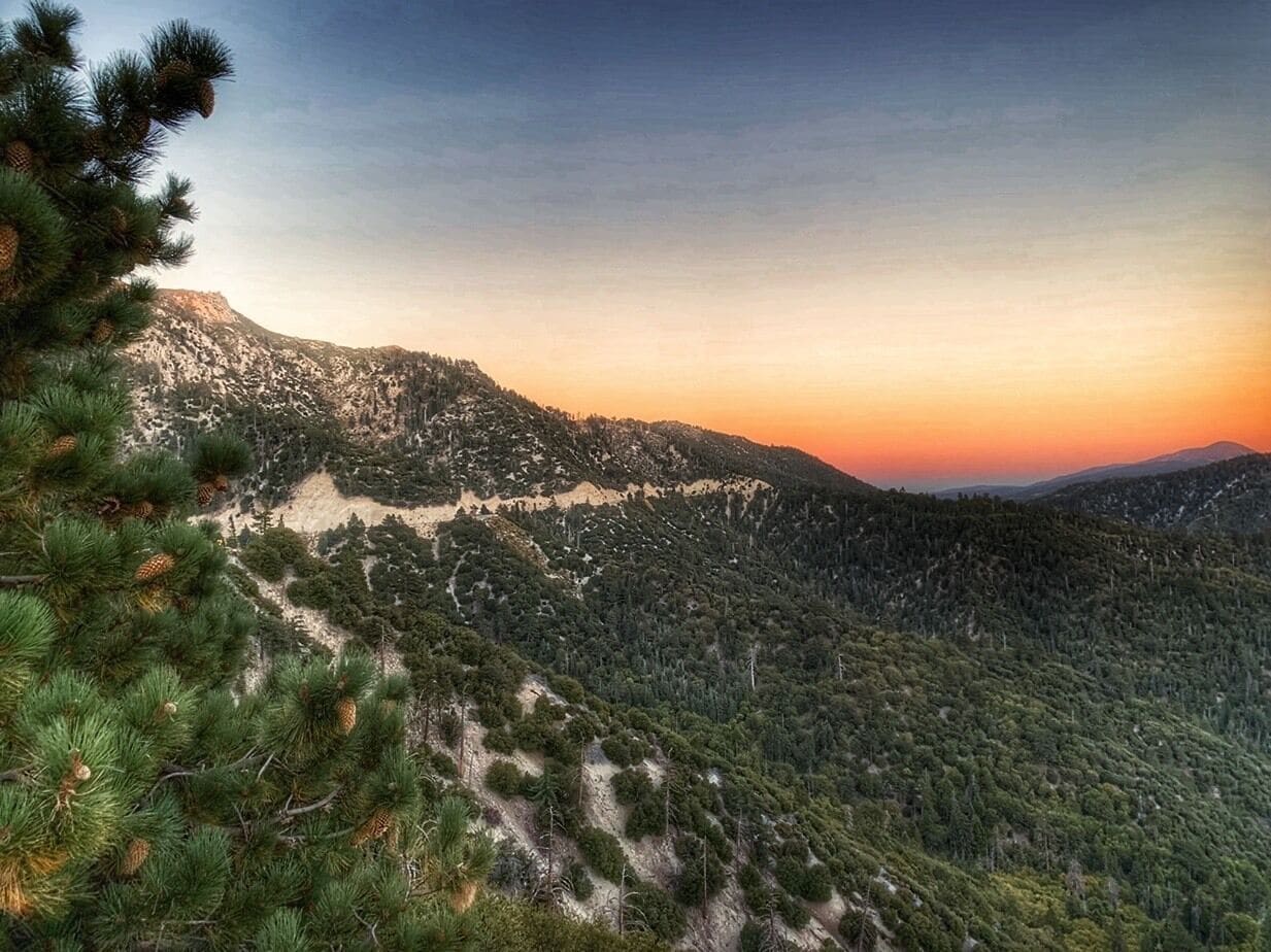 A mountainous landscape with dense forests and a clear sky.
