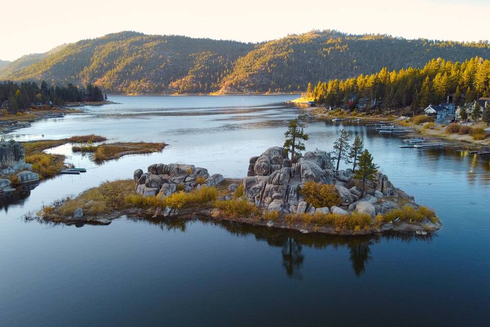Un llac tranquil amb una petita illa al centre, envoltat per turons boscosos.