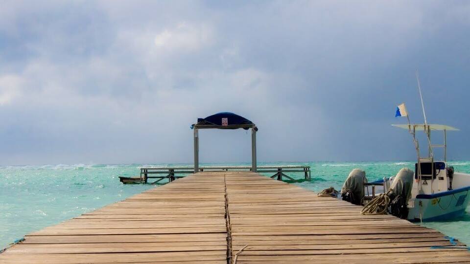 A wooden pier extending into turquoise waters with a boat docked at the end.