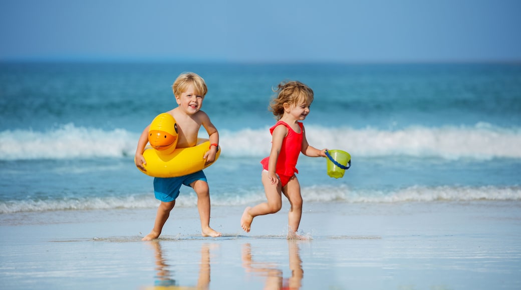 Boy with girl run holding inflatable buoys duck and toy at beach