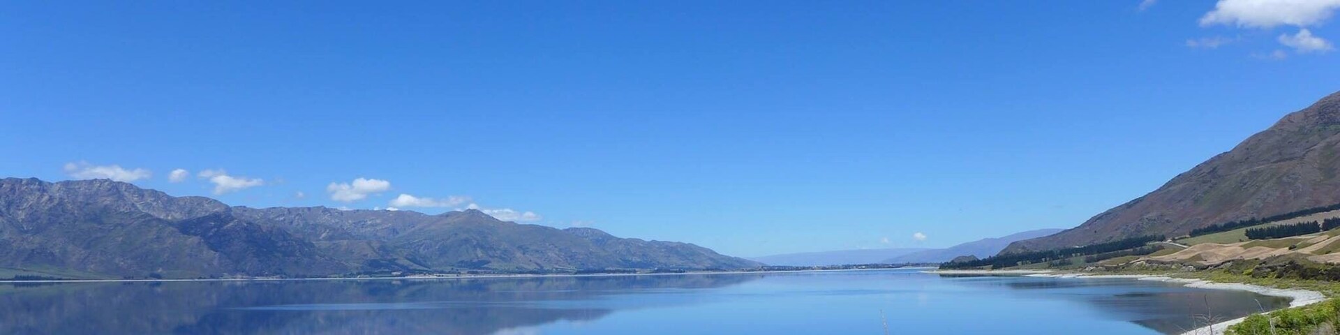 Un lago tranquilo rodeado de montañas bajo un cielo azul despejado.
