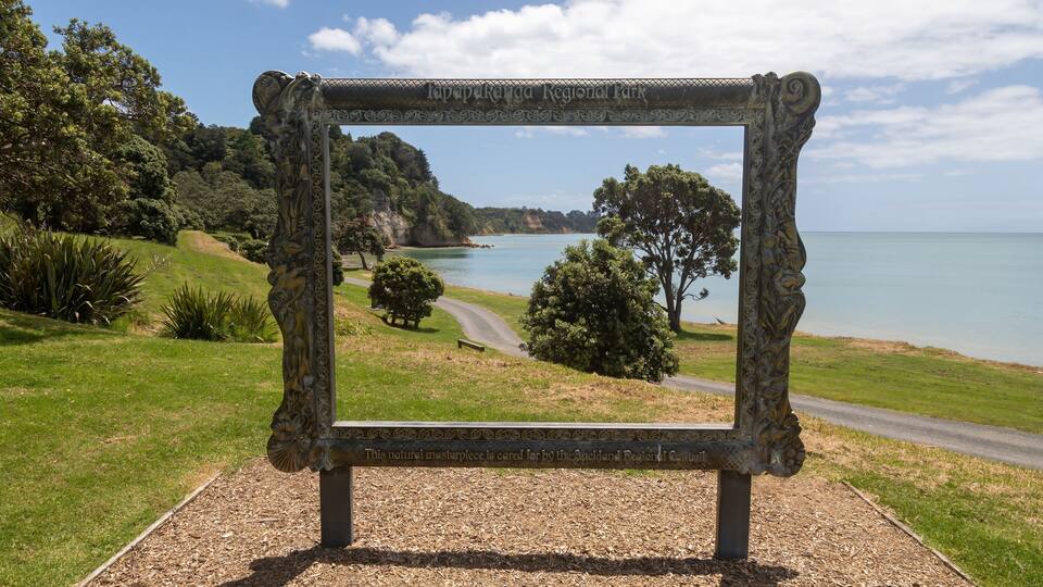 A scenic view through a decorative frame at Lavapekanga Regional Park, overlooking a coastal landscape with trees and a clear sky.