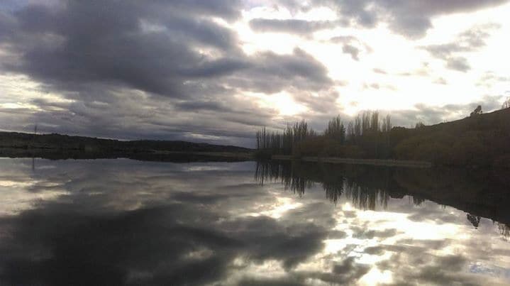 A calm lake reflecting clouds and trees.