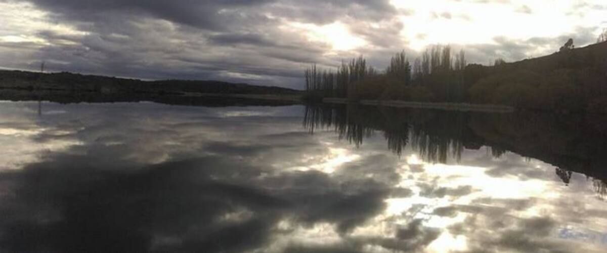 A calm lake reflecting clouds and trees.
