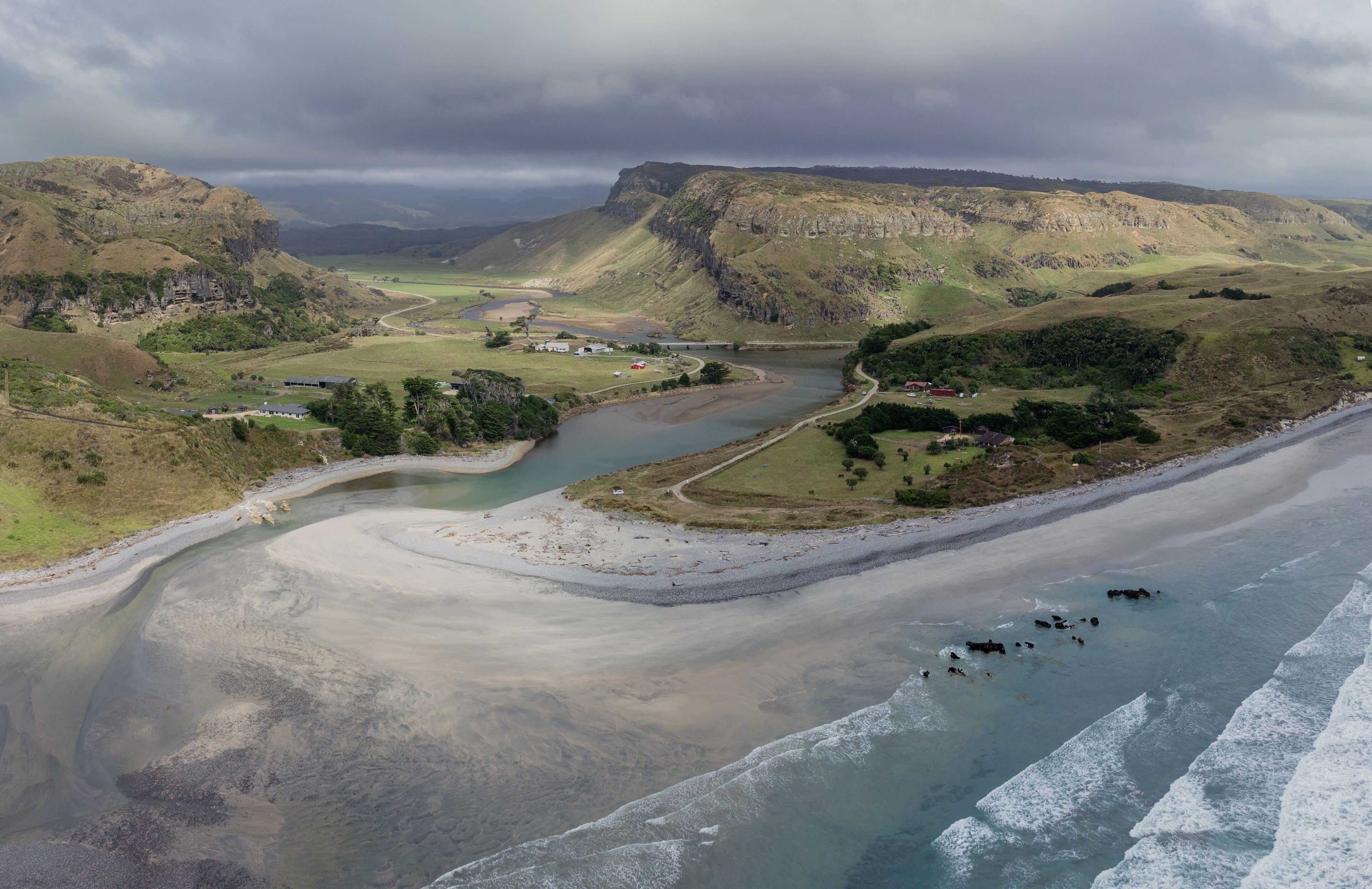 A river winding through a valley with cliffs and a beach.