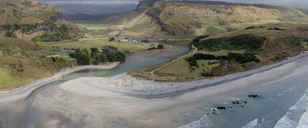 A river winding through a valley with cliffs and a beach.