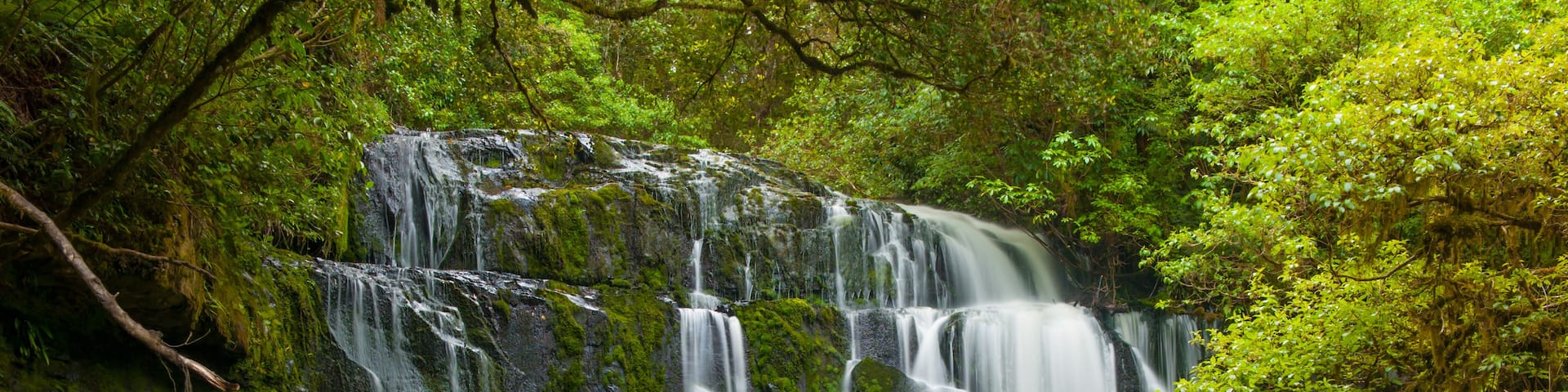 A multi-tiered waterfall surrounded by lush greenery.