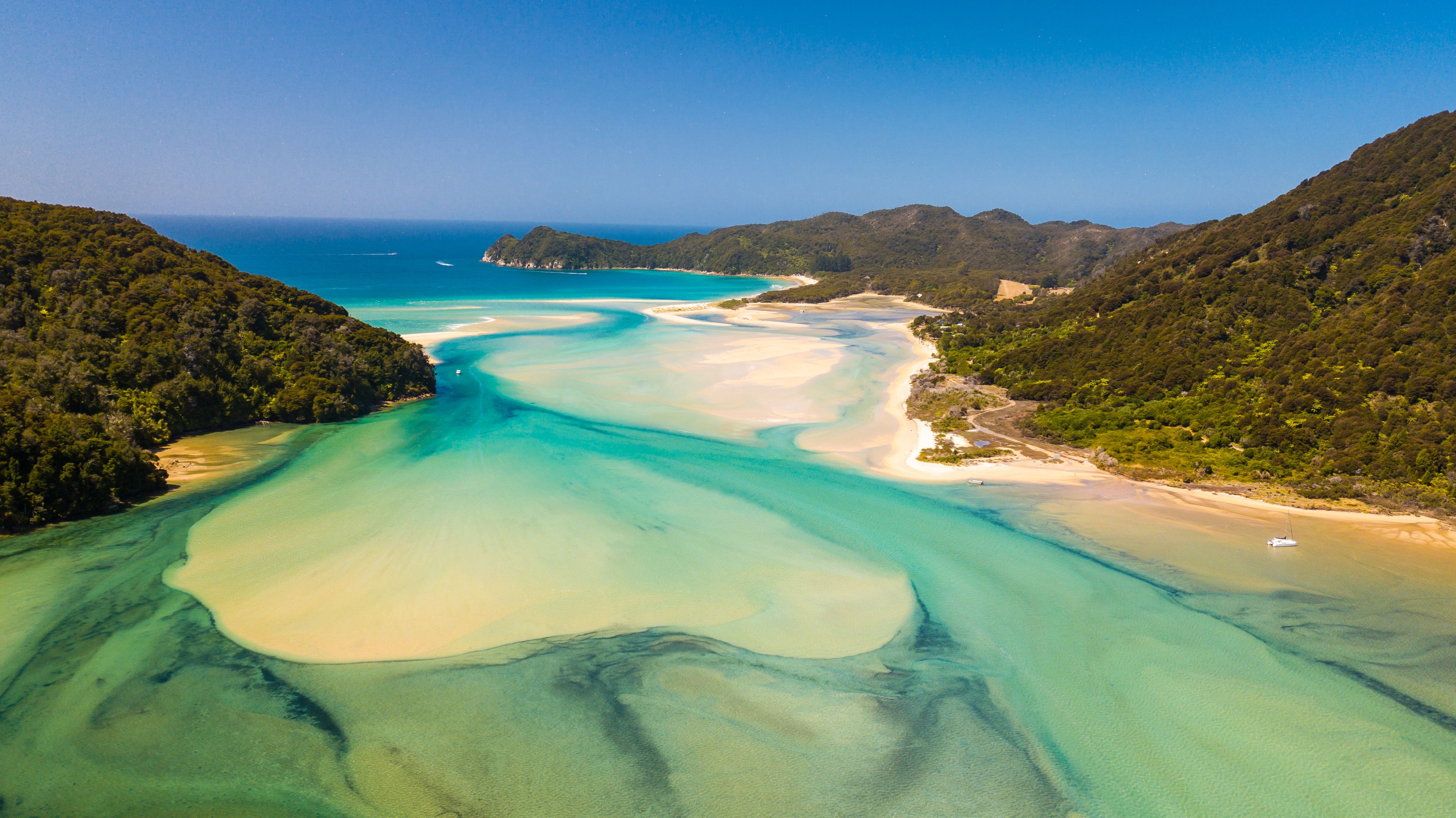 Turquoise tidal estuary between forested coastal hills