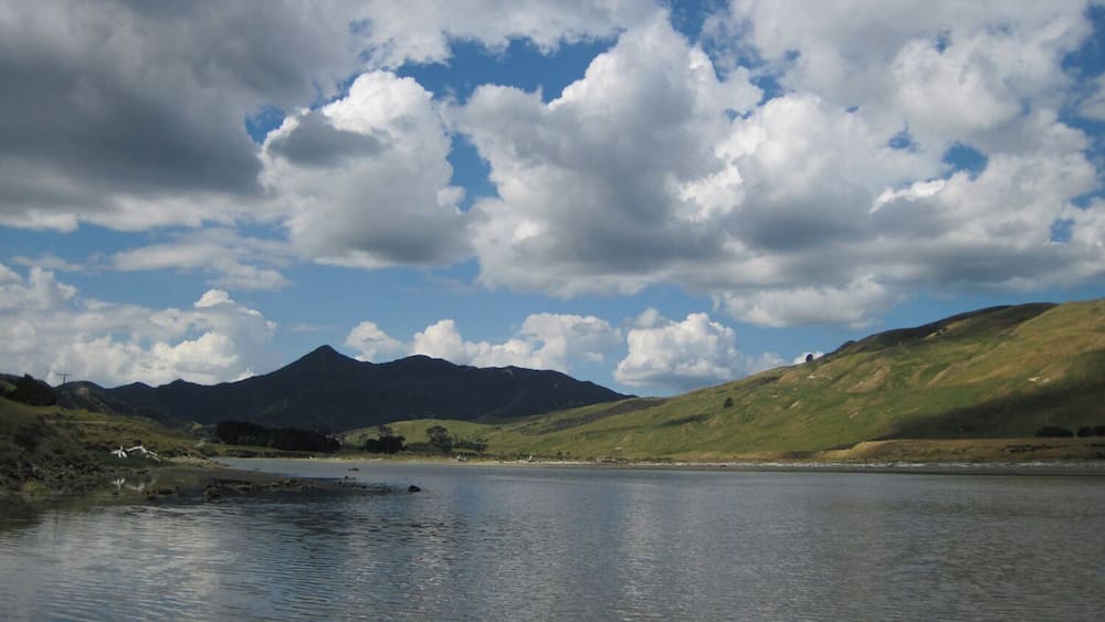 Un lac avec des montagnes en arrière-plan et un ciel partiellement nuageux.
