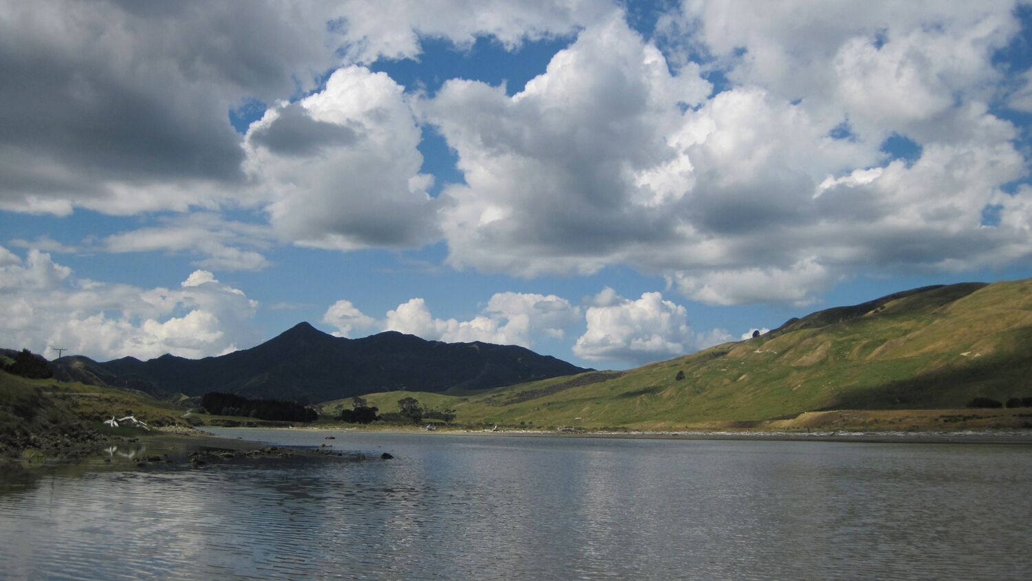 A lake with mountains in the background and a partly cloudy sky.