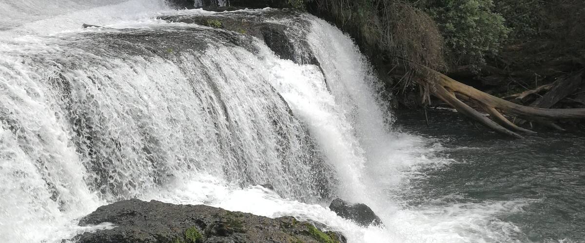 A waterfall cascading over rocks in a forested area.