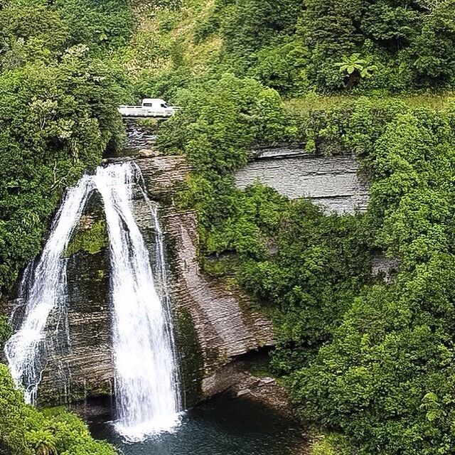 A waterfall cascading over a rocky cliff surrounded by lush greenery.