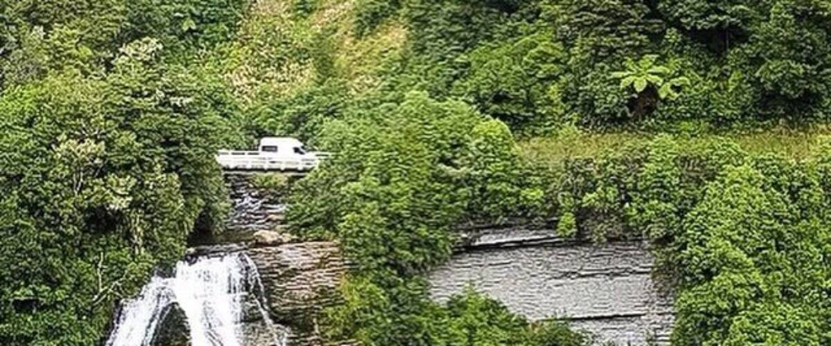 A waterfall cascading over a rocky cliff surrounded by lush greenery.