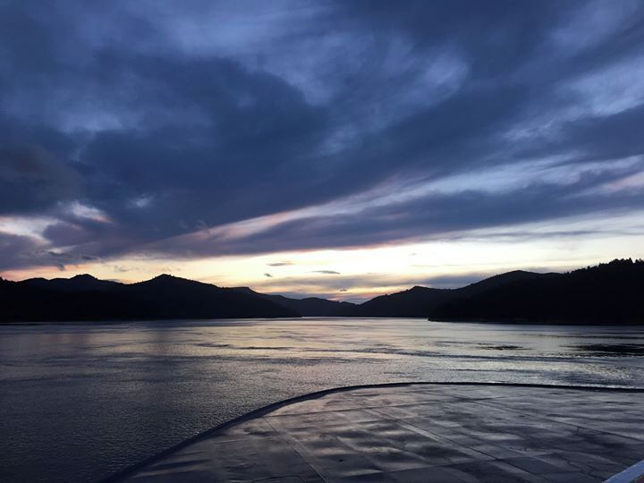 A calm lake at sunset with mountains in the background.