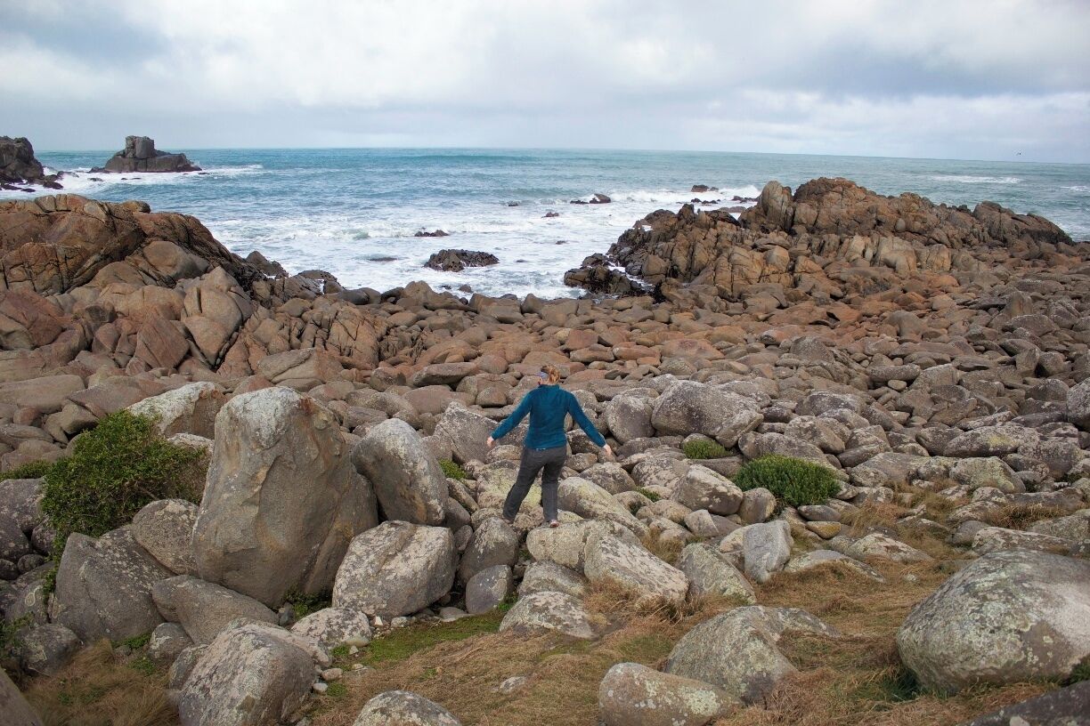 A rocky coastline with large boulders and waves crashing against the shore.