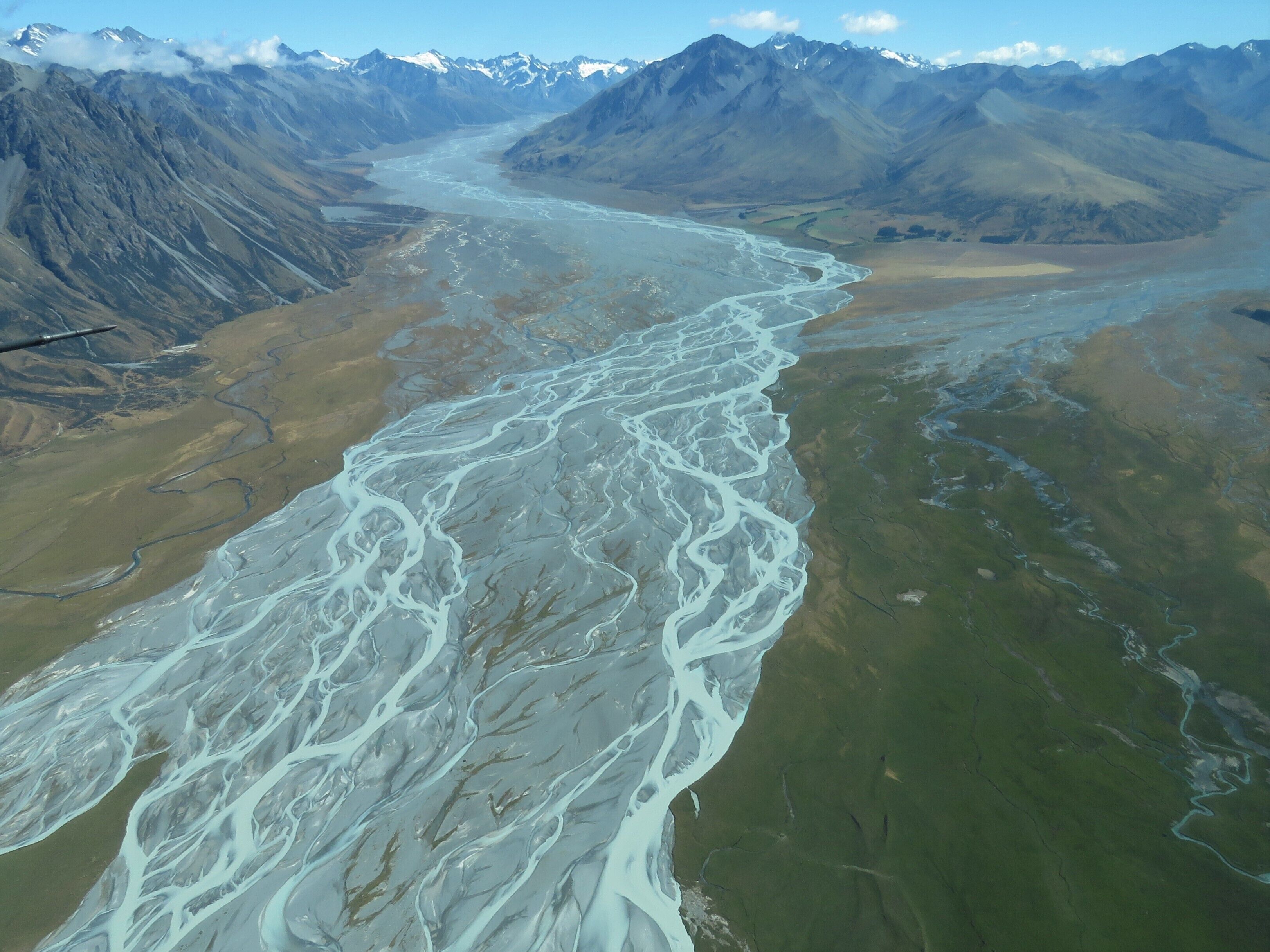 A river winding through a mountainous landscape with snow-capped peaks in the background.