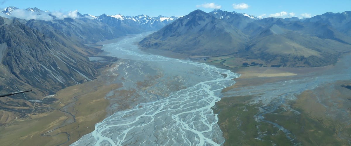 A river winding through a mountainous landscape with snow-capped peaks in the background.