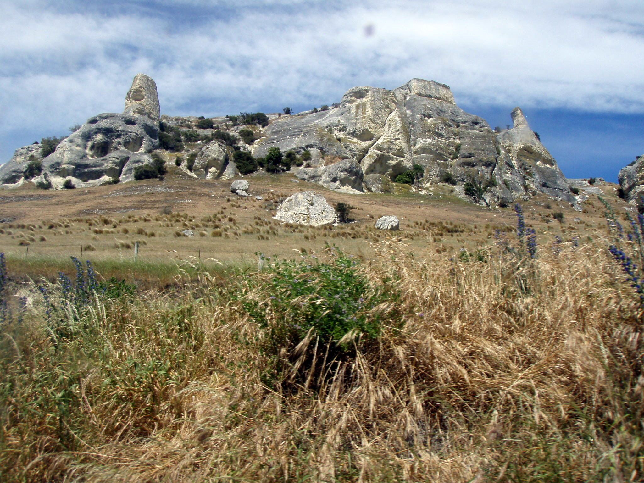 A rocky hill with sparse vegetation and a clear sky.