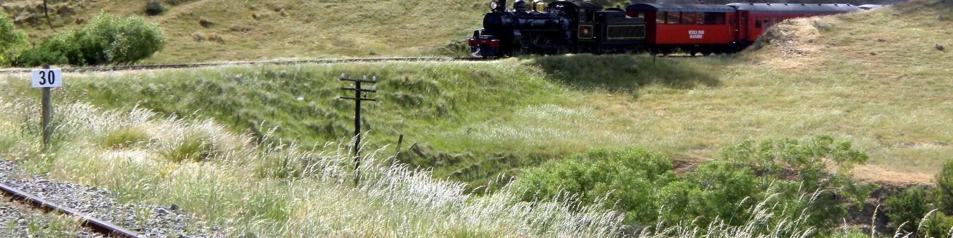 A steam locomotive on a railway track in a hilly landscape.