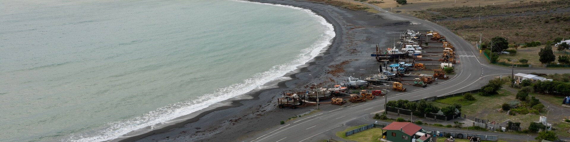 Una carretera costera con una playa a un lado y un paisaje montañoso en la distancia.