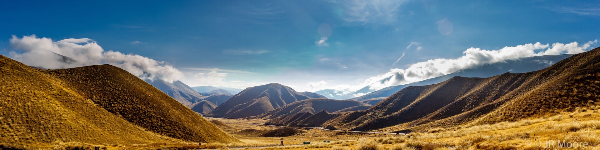 Un paisaje montañoso con una carretera serpenteante y un cielo despejado.