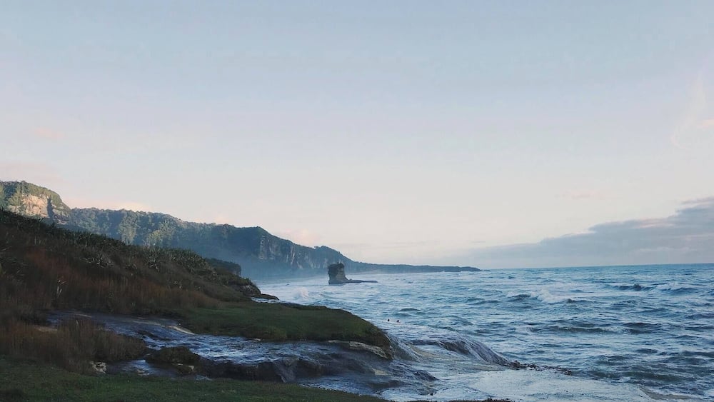 A coastal landscape with cliffs, a rocky outcrop, and a river.