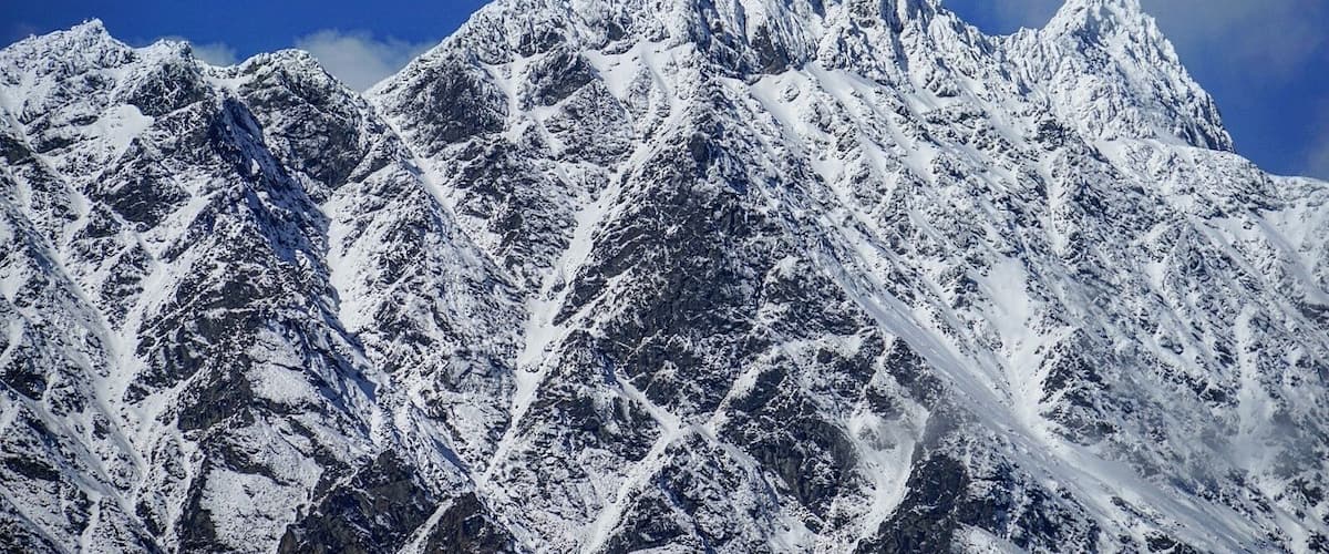 A snow-covered mountain range with sharp peaks and rugged terrain.