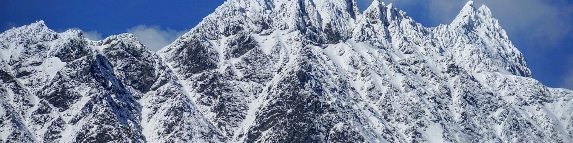 Uma cordilheira coberta de neve com picos acentuados e terreno acidentado.