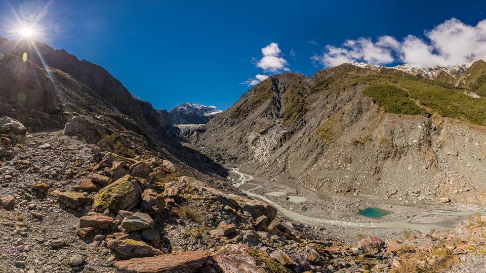 A mountainous landscape with a glacier, rocky terrain, and a turquoise lake.