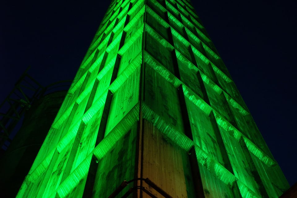 A tall building with green lighting at night.