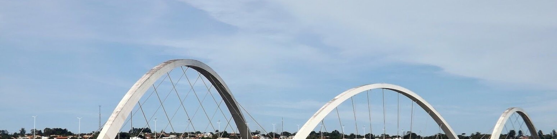 Uma grande ponte branca com duas arcos sobre a água, com um pequeno barco em primeiro plano.