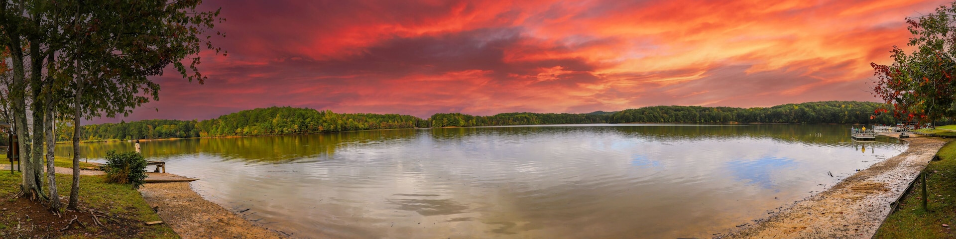 a stunning panoramic shot of the silky brown waters of the Chattahoochee river surrounded by green and autumn colored trees with powerful clouds at Sweetwater Creek State Park in Lithia Springs GA