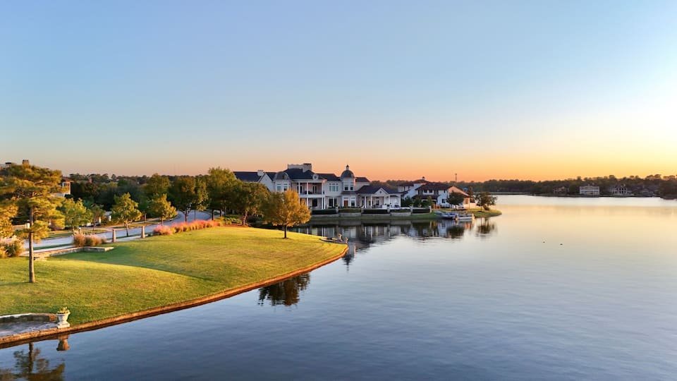 A large estate with a lake, surrounded by trees and a well-maintained lawn.